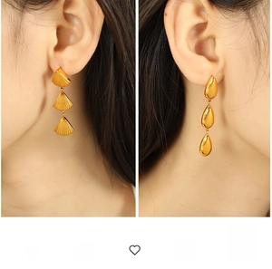 Close-up of golden multi-layer fan-shaped and teardrop-shaped dangle earrings on ears