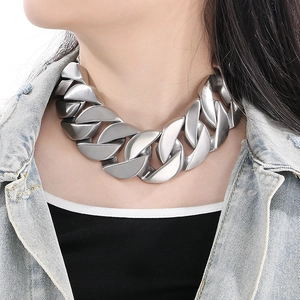 Close-up of a chunky silver matte Cuban link necklace worn with a denim jacket