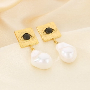 Detail of square gold hammer textured earrings with devil eye and baroque pearls