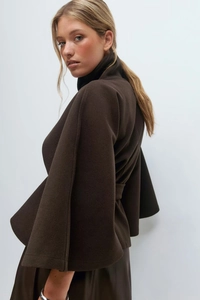 Detail of deep brown wool poncho coat with wide sleeves and waist-cinching silhouette