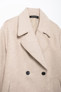 Détail du manteau en laine beige avec col à revers et boutons noirs à double boutonnage