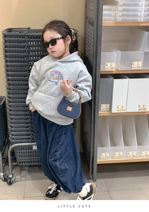 Tenue pour enfant avec sweat gris, pantalon en jean et mini sac à main en magasin