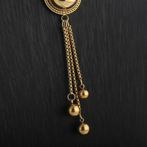 Detailed close-up of golden tassel fringe pendant with polished metal spheres