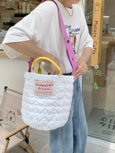Quilted white heart pattern tote bag with yellow handles and purple strap in outdoor scene