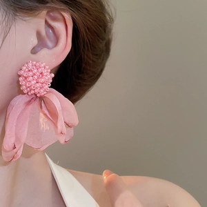 Detail of pink beaded flower earrings with multi-layered tulle petals worn by a model