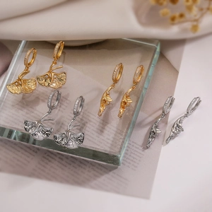 Golden and silver ginkgo leaf earrings with zircon on glass and silk background