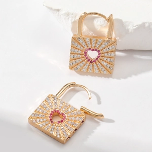 Detail of golden heart-shaped lock earrings with pink stone and white cubic zirconia