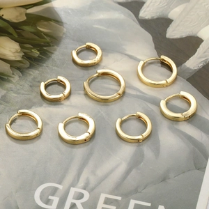 Set of minimalist golden huggie earrings in various sizes on floral magazine background