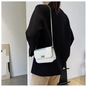 Borsa a tracolla trapuntata bianca indossata da una modella su un blazer nero