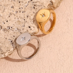 Macro detail of gold and silver North Star signet rings with zircon on stone