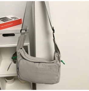 Detail of light gray water-resistant nylon messenger bag with green zipper puller