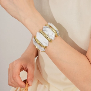 Vue détaillée d'un large bracelet géométrique avec texture marbre blanc et détails dorés