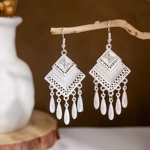 Detailed shot of ethnic peacock bell tassel earrings hanging on a natural branch