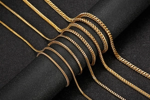 Detailed view of various widths of golden stainless steel chains on dark display