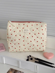Detailed view of quilted makeup bag with red hearts and secure zip closure