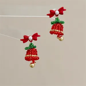 Detail of beaded Christmas bell earrings with red bows and gold metallic accents