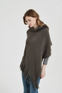Detail of brown knitted poncho featuring a plush faux fur collar and long fringe hemline