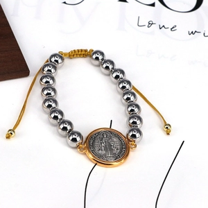 Close-up of Saint Benedict religious medal with silver beads and yellow adjustable cord