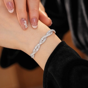 Détail macro du bracelet torsadé argenté serti de zircons sur fond de velours noir