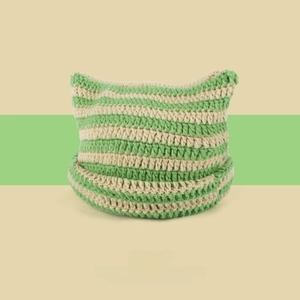 Detail of green striped knit beanie with cute cat ears and thick yarn texture