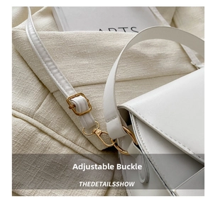 Detail of adjustable gold buckle and hook on a white textured faux leather saddle bag