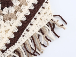 Macro shot of boho knit vest featuring textured crochet wave patterns and fringe detail