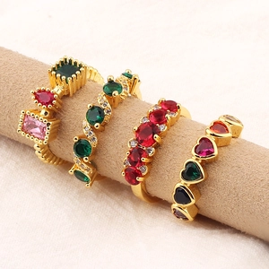 Set of four gold-plated rings with emerald-cut colored zircons on a beige jewelry display