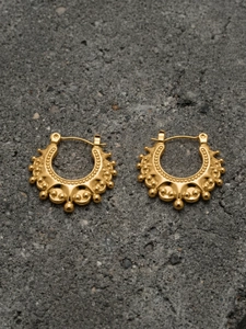 Detailed macro view of gold-plated U-shaped crown earrings with steel bead textures