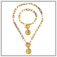 Detailed macro view of gold flower chain necklace and bracelet set with coin pendant