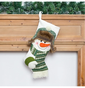 Detail of a white knit Christmas stocking featuring a snowman on a wooden fireplace