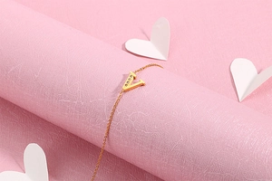 Detail view of a gold-plated V-shaped charm with sparkling inlaid white crystals