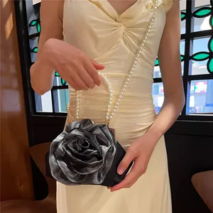 Detail of silver rose-shaped evening clutch bag with elegant white pearl strap handle