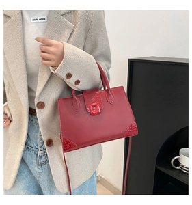 Detail view of burgundy faux leather handbag with crocodile pattern and square clasp