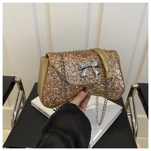 Detail of gold sequin handbag with silver bow accent and metallic chain strap