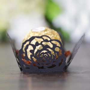 Detail of laser-cut black paper rose cupcake liner holding a chocolate on wood