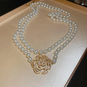 Détail macro du collier de perles double épaisseur avec pendentif fleur de camélia serti