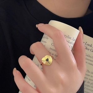 Close-up of golden 925 silver ring with black heart and radial textured engraving