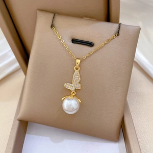 Detail of gold butterfly necklace with rhinestones and a white pearl in a gift box