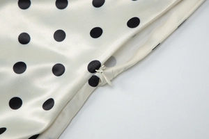 Dettaglio della cerniera invisibile su un abito in raso bianco a pois neri chic