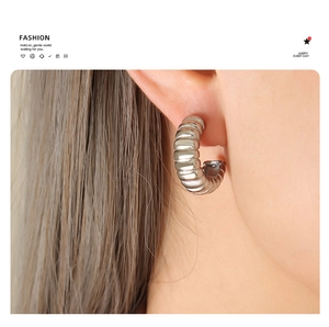 Close-up of silver C-shaped ribbed hoop earrings showing elegant metallic texture
