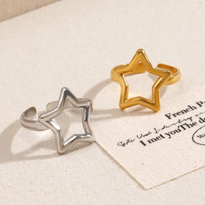 Minimalist gold and silver star cutout stainless steel rings on a textured fabric