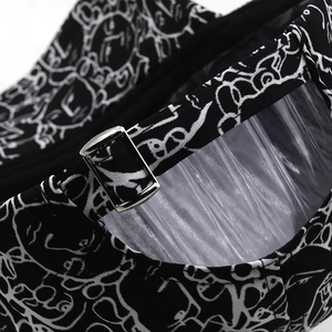 Detail of black baseball cap showing white abstract graffiti print and silver metal buckle