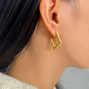 Chic gold geometric earrings with textured twist design shown on a model's ear