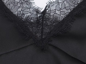 Detailed close-up of V-neck with intricate black eyelash lace trim on satin fabric