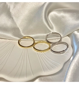 Macro view of gold and silver S925 sterling silver hoop earrings on a shell tray