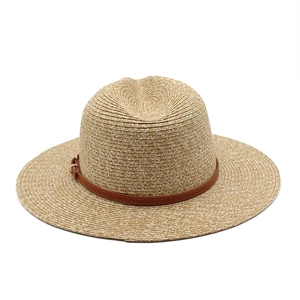 Detailed close-up of woven straw panama hat featuring a brown faux leather buckle band