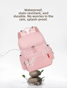 Pink diaper backpack with diamond quilting showing water splashing on waterproof fabric
