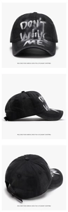 Detail of black baseball cap with white graffiti letters and adjustable strap