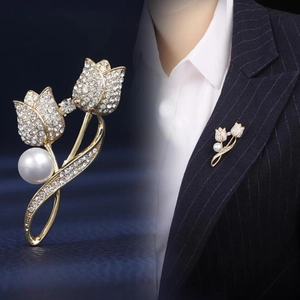 Elegant gold tulip brooch with white crystals and pearl shown on a black suit blazer