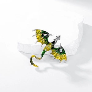 Detail of dragon brooch with green enamel wings and sparkling zircon scales on white stone
